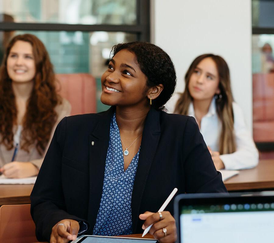 female students smiling and taking notes at 拼搏体育